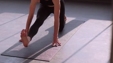 Sabah pilatesi. Ayrılma egzersizi. Egzersiz yoga yapan sağlıklı bir kadın güneş ışınları jimnastik salonundaki spor minderinde asana kas esneme egzersizi yapıyor..