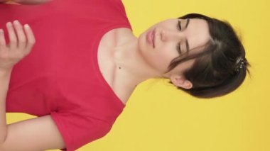 Dikey video. Alışveriş fiyaskosu. Hayal kırıklığına uğramış, kayıp kadın çantaları sarı boş alanda izole edilmiş..