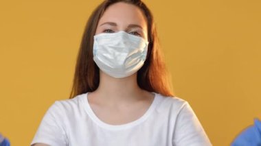 Sağlık hizmetleri. Romantik sinyal. Bağlılık mesajı. Koruyucu maskeli iyimser kadın eldivenler havada öpüşürken sarı fotokopi alanında izole edilmiş kalp hareketi gösteriyor..