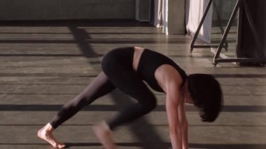 Denge motivasyonu. Esneme egzersizi. Aktif giyinen sağlıklı bir kadın yoga esnekliği egzersizi yapıyor. Boş spor salonu stüdyosunun içinde tek başına egzersiz yapıyor..