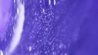 Dikey video. Köpüklü sıvı. Serum jeli. Odaklanmamış neon mavisi simler şeffaf emülsiyon dokusu boya su karışımı hareket soyut sanat arkaplanı.