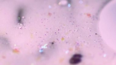 Işıldayan emülsiyon. Parlak sıvı. Pembe, şeffaf, pembe, parlak pullu parçacıklar. Su jölesi, mürekkep damlaları, soyut sanat arkaplanı. Bokeh ışıkları..