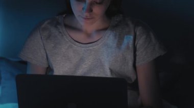 Gece işi. Serbest teslim tarihi. Uykusuzluk teknolojisi. Gece geç saatlerde yatakta bilgisayarla yazı yazan rahat bir kadın. Karanlık ev yatak odası..