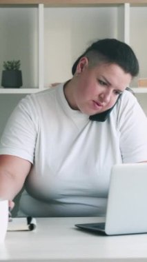 Dikey video. Ofis müdürü. Yönetici işçi. Aşırı kilolu kadın sekreter istemciye danışmanlık çoklu görev cevaplama çağrı yazma tarayıcı.