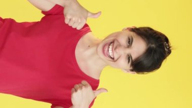 Dikey video. Destek jesti. Neşeli kadın. Onaylıyorum, gülümseyen, mutlu, kendine güvenen, sarı, boş alan arka planında izole edilmiş..
