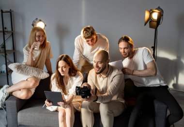 Takım projesi. Fotoğraf stüdyosu. Işık odasındaki neşeli insanlar iş fikirlerini yazarak dostça tartışıyorlar. Kırılma sırasında beyin fırtınası.