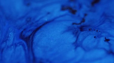 Damlayan ışıltılı doku. Akışkan sanat. Odaklanamayan mavi renkli parıldayan parçacıklar akrilik mürekkep dalgaları koyu soyut hipnotik gizemli uzay arkaplanı üzerinde hareket ediyor.