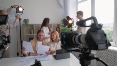 Stüdyo ekibi. Grup tartışması. Uzman aydınlatmacılardan oluşan çeşitli ekipler spot ışıklarını ayarlıyor. Video çekim aydınlatma ekipmanlarına hazırlanıyorlar..