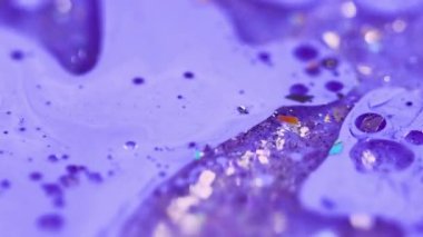 Işıldayan jel. Köpüklü yağ damlası. Odaklanmamış mor renkli parlak parçacıklar akrilik akrilik sıvı mürekkep dökülmesi, soyut sanat arka planı ve bokeh ışıkları..