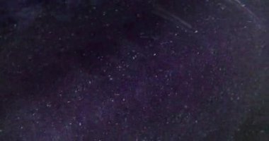 Görüntü pırıl pırıl. Barut parçacıkları. Parlak parlak noktalar parıldayan toz, soyut mor arka planda kıvrılıp duruyor..