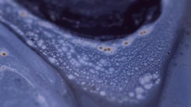 Parıltı yayılıyor. Boya damlası. Bulanık mavi, siyah, parlak, tahıl rengi, ıslak, mürekkep, su karışımı, soyut sanat arka planı..