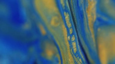 Mürekkep döküldü. Köpüklü sıvı. Odaklanmamış mavi altın renkli sim parçacıkları dokusu dalga emülsiyonu soyut sanat arkaplanı.