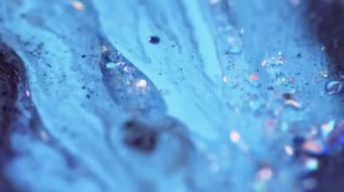 Işıl ışıl. Sıvı sim damlası. Odaklanmamış mavi renk parıldayan metalik pullu parçacıklar mürekkep emülsiyon karıştırma sıvı dökülme hareketi soyut sanat arka planı.