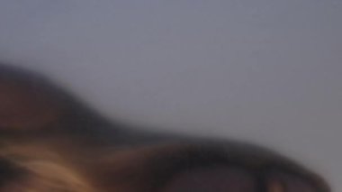 Dikey video. Kadın kederi. Özgürlük arzusu. Kırışık şeffaf polietilen filmin arkasında sıkışmış rahatsız bir kadın..