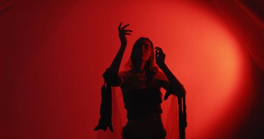 Ruhani dans. Ruhun iyileşmesi. Transta olan rahat kadın silueti polietilen paçavralar giyerek koyu kırmızı fotokopi arkaplanında izole edilmiş zarif el hareketleri yapıyor..