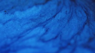 Damlayan doku. Parıltılı boya akışı. Karanlık soyut sanat arka planında odaksız mavi renkli parıldayan parçacıklar akrilik mürekkep dalgası hareketi.