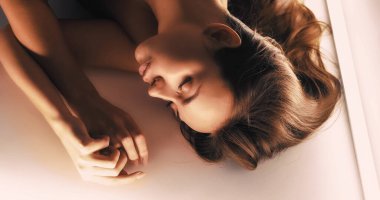 Güzellik portresi. Kadınsı hassasiyet. Huzurlu, muhteşem, şehvetli esmer kadın. Mükemmel bir yüzü olan, açık arka planda uyuyan..