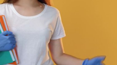 Güvenlik onayı. Karantina sınıfı. Koronavirüs salgını. Korunaklı yüz maskesi eldivenli kendine güvenen bayan öğretmen sarı fotokopi alanında parmak izini gösteren kitaplarla..