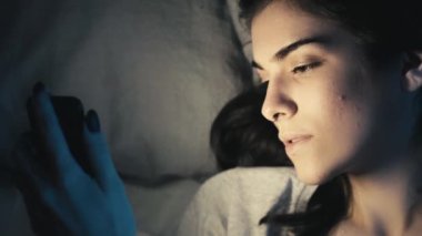 Gece online. Uyku zamanı aleti. Mobil uykusuzluk. Uykucu kız, internetten telefon kullanıyor internette geziniyor, geç saatlere kadar yatakta esniyor..