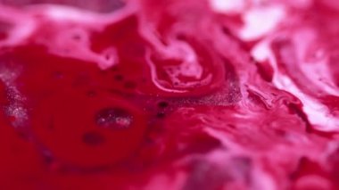 Boya dalgası. Parıldayan sıvı dökülmüş. Odaklanmamış beyaz pembe renk parıldayan pullu parçacıklar sıvı mürekkep pigmenti boya harmanlama hareketi soyut sanat arkaplanı.