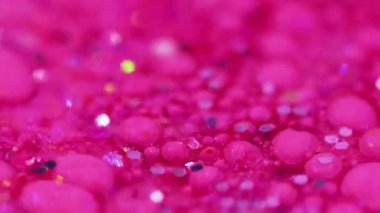Işıldayan kabarcıklar. Parlak sıvı doku. Odaklanmamış pembe renkli ışıltılı pullu parçacıklar boya damlaları yüzen döküntü cam küp kenar soyut sanat arka planı.