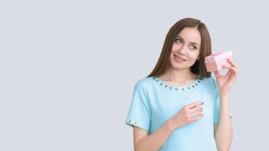 Hediye partisi. Tatil sürprizi. Özel gün kutlaması. Mavi elbiseli meraklı mutlu kadın ışık fotokopi alanında izole edilmiş bir kutuda tahmin yeteneği..