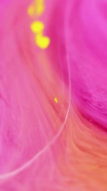 Dikey video. Gradyan boya. Parlak sıvı. Odaklanmamış pembe turuncu renk akan şeffaf damla emülsiyonu ışıltılı parçacıklar güzellik mürekkebi deseni soyut sanat arka planı.