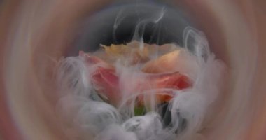 Duman sıvısı. Yaprak dumanı. Beyaz şeftali rengi boya damlası gül çiçeği tomurcuğunu kaplıyor. Odaklanmamış yuvarlak mercek soyut bulanık arkaplan.