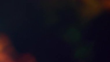 Işık bulanıklığı. İşaret fişeği soyut. Işıldayan sarı turuncu mavi çok renkli parlak yanıp sönen ışıklar karanlık sanat arka planında hareket ediyor..