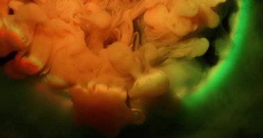 Duman girdabı. Hipnoz sıvısı. Portakal rengi sanat karışımı mürekkep siyah geceye dökülüyor soyut bir arka plan parıldıyor. Yeşil gökkuşağı ışığı yuvarlak su lensi.