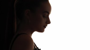 Dalgın bir yüz. Güzellik silueti. Beyaz boş arkaplanda izole edilmiş, sakin, barışçıl bir kadının koyu renk karşıtlık profili..