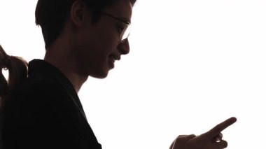 Birkaç siluet. Romantik sohbet. Mesafe ilişkisi. Telefon mesajları kullanan mutlu bir adamın, beyazlar içinde izole edilmiş sevgilisine canlı yayında öpücük yollamasının karanlık profili..