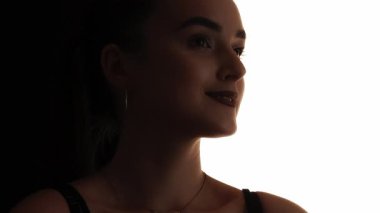 Güzellik silueti. Yüz hatları. Tatmin olmuş, gururu okşanmış, beyaz fotokopi arkaplanında izole edilmiş gülümseyen bir kadının koyu renk karşıtlığı..