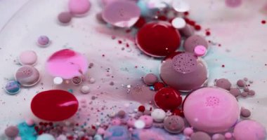 Baloncuk döküldü. Mürekkep akışı. Yağ rengi damlaları suda çözünüyor. Kırmızı pembe beyaz akrilik pigmeler köpük soyut sanat arka planı.