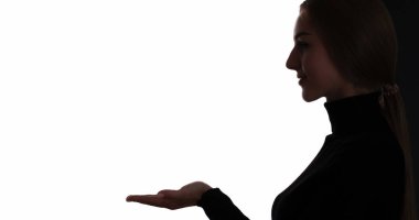 Kadın reklamcılığı. Özel fiyat. Karanlık profil kendinden emin kadın silueti, beyaz arkaplanda avuç içi açık fotokopi alanını gösteriyor..