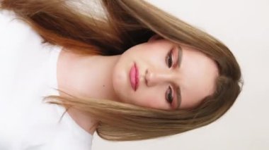 Dikey video. Saç sorunu. Vitamin eksikliği. Beyaz tişörtlü tatminsiz kadın, hafif fotokopi arkaplanda izole edilmiş hasarlı kötü sonlara bakıyor..