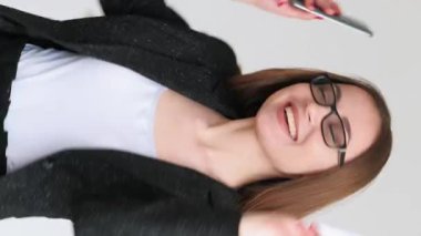 Dikey video. İyi gelir. Başarılı bir yatırım. Şaşırtıcı mutlu iş kadını akıllı telefon kredi kartıyla nötr bir şekilde dans etmeyi kutluyor..