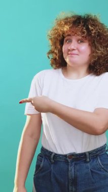 Dikey video. Tavsiye edilen insanlar. Özel fiyat. Heyecanlı, mutlu, kıvırcık saçlı, kıvırcık saçlı, mavi üzerine izole edilmiş bir kız..