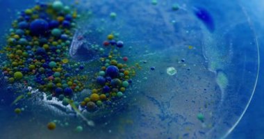 Yağ sıvısı. Su damlasını boya. Mavi suda yüzen odaksız renkli kabarcıklar. Patlayan jel dokusu serumu soyut sanat arkaplanı.