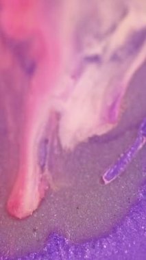 Dikey video. Islak sim. Boya dökülmüş. Damla mürekkebi. Odaklanmamış mor, pembe, gümüş rengi, ışıltılı, ışıltılı, sıvı, sızıntı, su dokusu, soyut sanat arka planı..