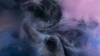 Mürekkep karıştırıyorum. Dumanı karıştır. Odaklanmamış siyah mavi çok renkli bulanık boya bulutu soyut sanat arka planında ışıldayan su.