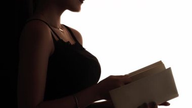 Siluet okunuyor. Bilgi araştırması. Zekice bir hobi. Beyaz kopya arkaplanda kitap izole edilmiş zarif bir kadının koyu renk karşıtlık profili ana hatları.
