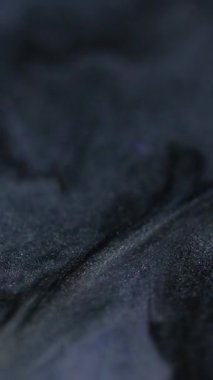 Dikey video. Sihirli parıltı. Mürekkep emülsiyonu. Siyah lavanta rengini karıştıran koyu mor çözünmüş köpüklü sıvı. Parıldayan parçacıklar boya dokusu arka planı..