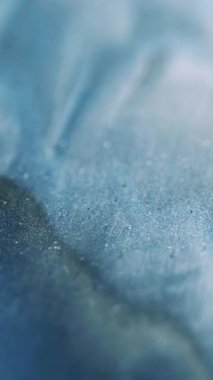 Dikey video. Dalga hareketi. Köpüklü sıvı. Işıldayan parlak mavi sıvı parlayan parçacıklar hipnotik soyut sanat arka planında parlak doku akışı.