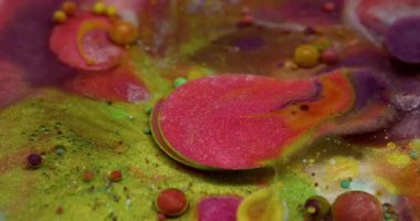 Işıldayan akış. Parlak boya damlası. Renkli akrilik jel köpüklü barut suyuna dökülüyor. Yeşil pembe sıvı karışımı soyut arkaplan.