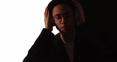 Müzik ilhamı. Ses teknolojisi. Koyu renk siluet, rahat bir adam. Beyaz siyah kulaklıkla müzik dinlemekten zevk alıyor..