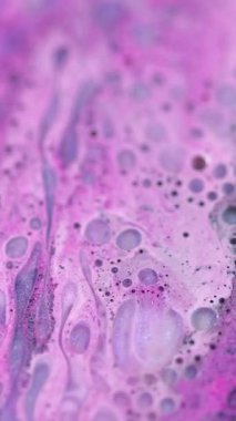 Dikey video. Boya damlası. Yağ sıvısı. Odaklanmamış pembe mavi renk parıltılı mürekkep parlak köpük parçacıkları akış hareketli ıslak doku soyut sanat arka planı.