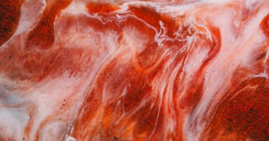 Pigment karışımı. Kimyasal parıltı. Turuncu bakır beyaz boya parıldayan sıvı dokuya yayılmış. Pürüzsüz karışık parçacıklar soyut arkaplanı bulanıklaştırır.