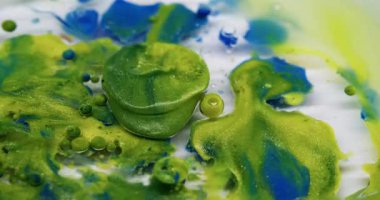 Işıldayan akış. Parlak boya damlası. Pudra suyuna dökülen renkli akrilik jel. Yeşil mavi sıvı karışımı soyut arkaplan.