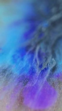 Dikey video. Akrilik mürekkep. Parıltı emülsiyonu. Boya su sıçratır altın akışı sıvı mavi mor parıldayan parçacıklar soyut renkli arkaplan tasarımı.